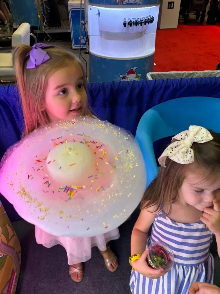Two children, one holding a large flower-shaped cotton candy.